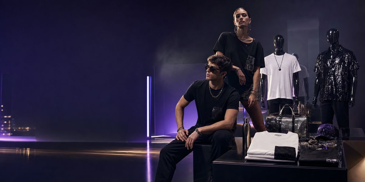 Due modelli e manichini con capi Melomania in uno spazio buio con luce viola